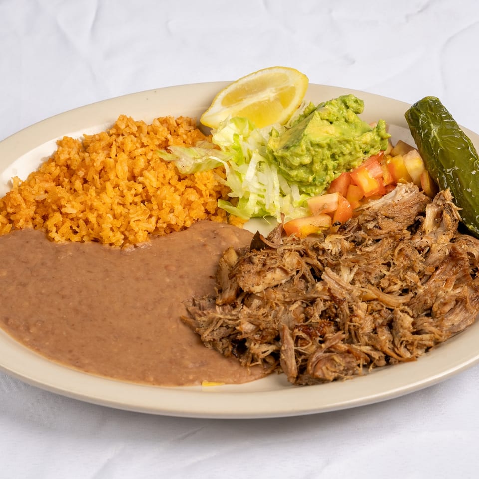 Carnitas served with rice, refried beans and guacamole.
