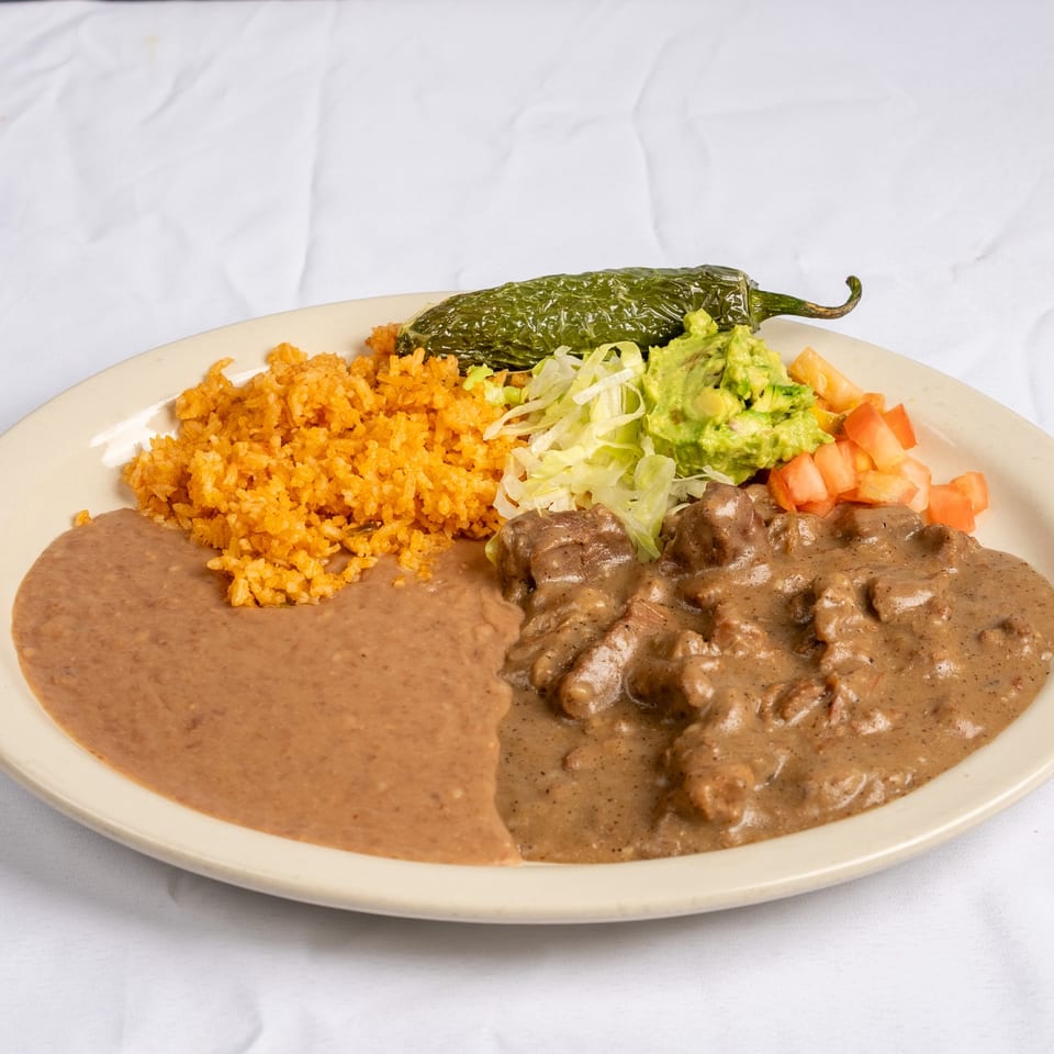 Carne guisada with sides and a roasted green pepper.