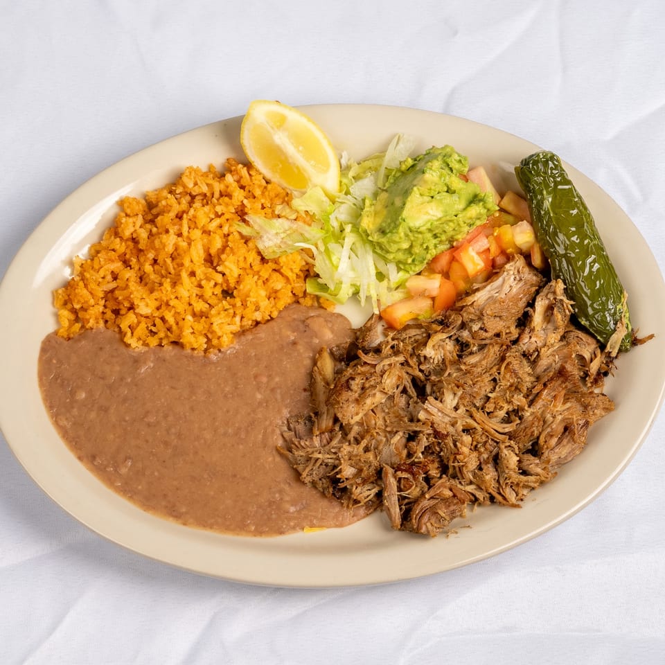Carnitas plate with rice, beans and a roasted pepper.